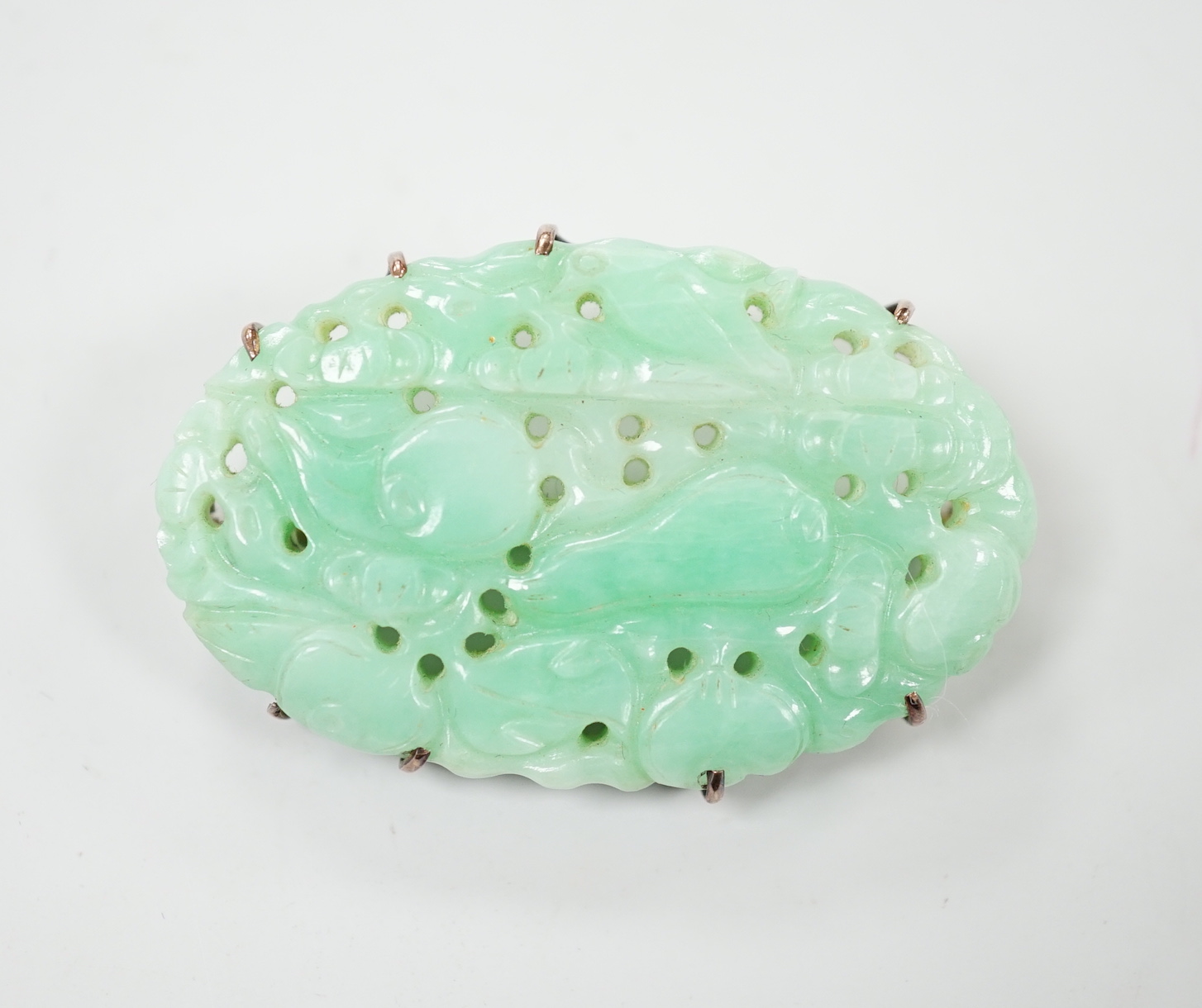 A Chinese yellow metal mounted carved jade oval brooch, 43mm, gross weight 15.8 grams